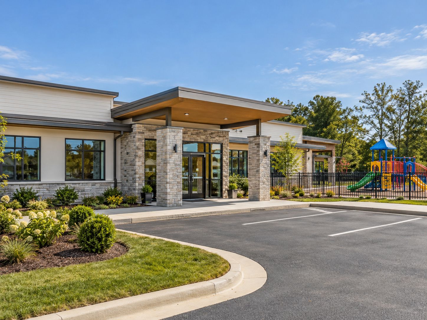 A modern single story childcare center with a covered entrance and a fenced playground